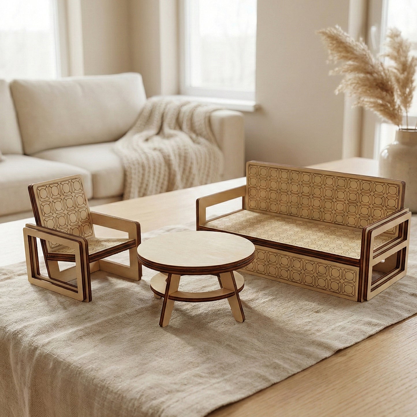 A modern lounge furniture set for dollhouses made of laser cut plywood. Includes a sofa and armchair with engraved geometric patterns and a round coffee table. Arranged on a linen runner in a bright, Scandi-style living room.