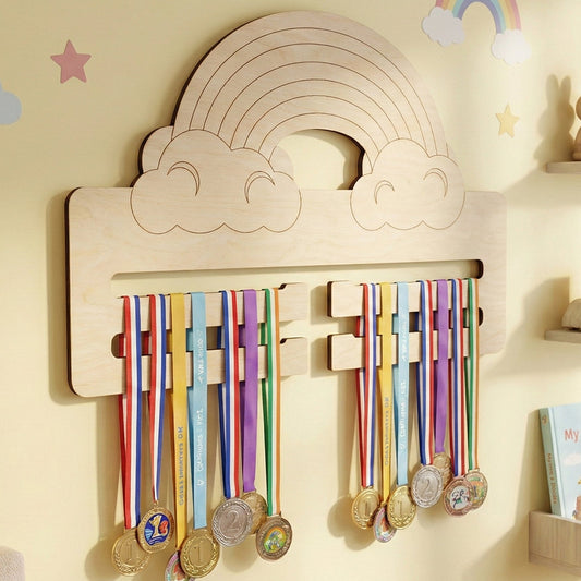 Laser cut plywood medal holder shaped like a rainbow arched over two clouds. Several gold and silver medals hang from two horizontal display bars. The light wood rack is mounted on a yellow wall decorated with star and rainbow decals.