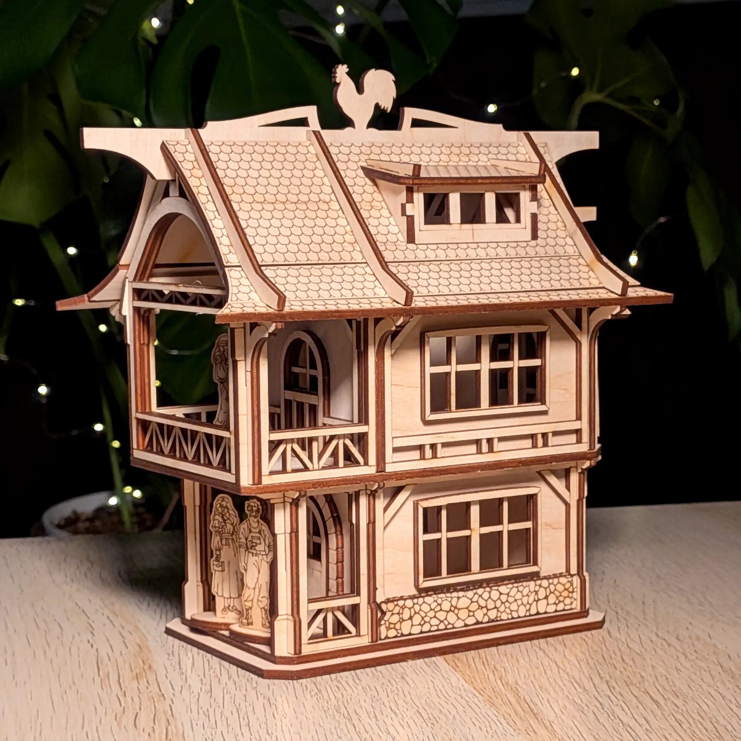 Three-quarter view of a medieval laser cut plywood townhouse with open balconies, archways, and tiny wooden people figures.