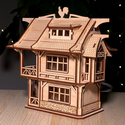 Side shot of an assembled medieval laser cut plywood townhouse showcasing detailed windows and a stone textured foundation.