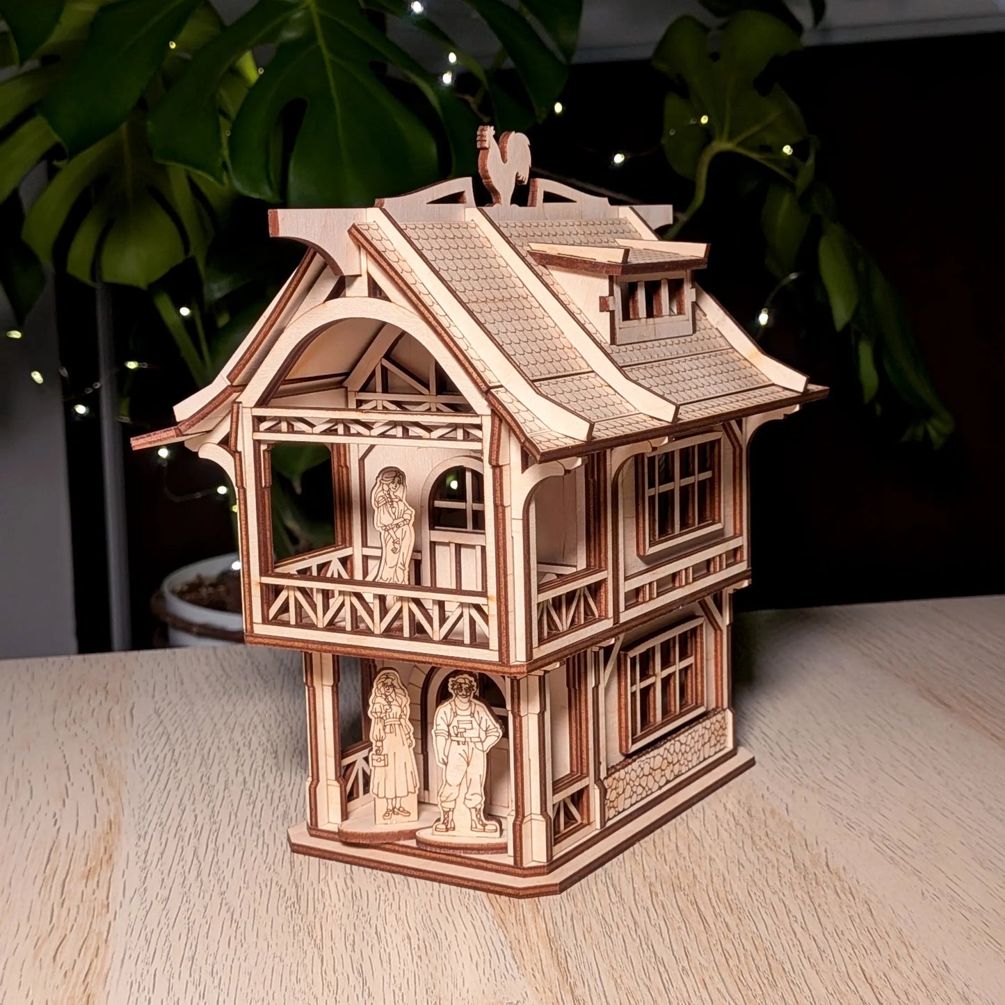 Medieval laser cut plywood townhouse model on a table with three miniature wooden resident figures placed on the balconies.