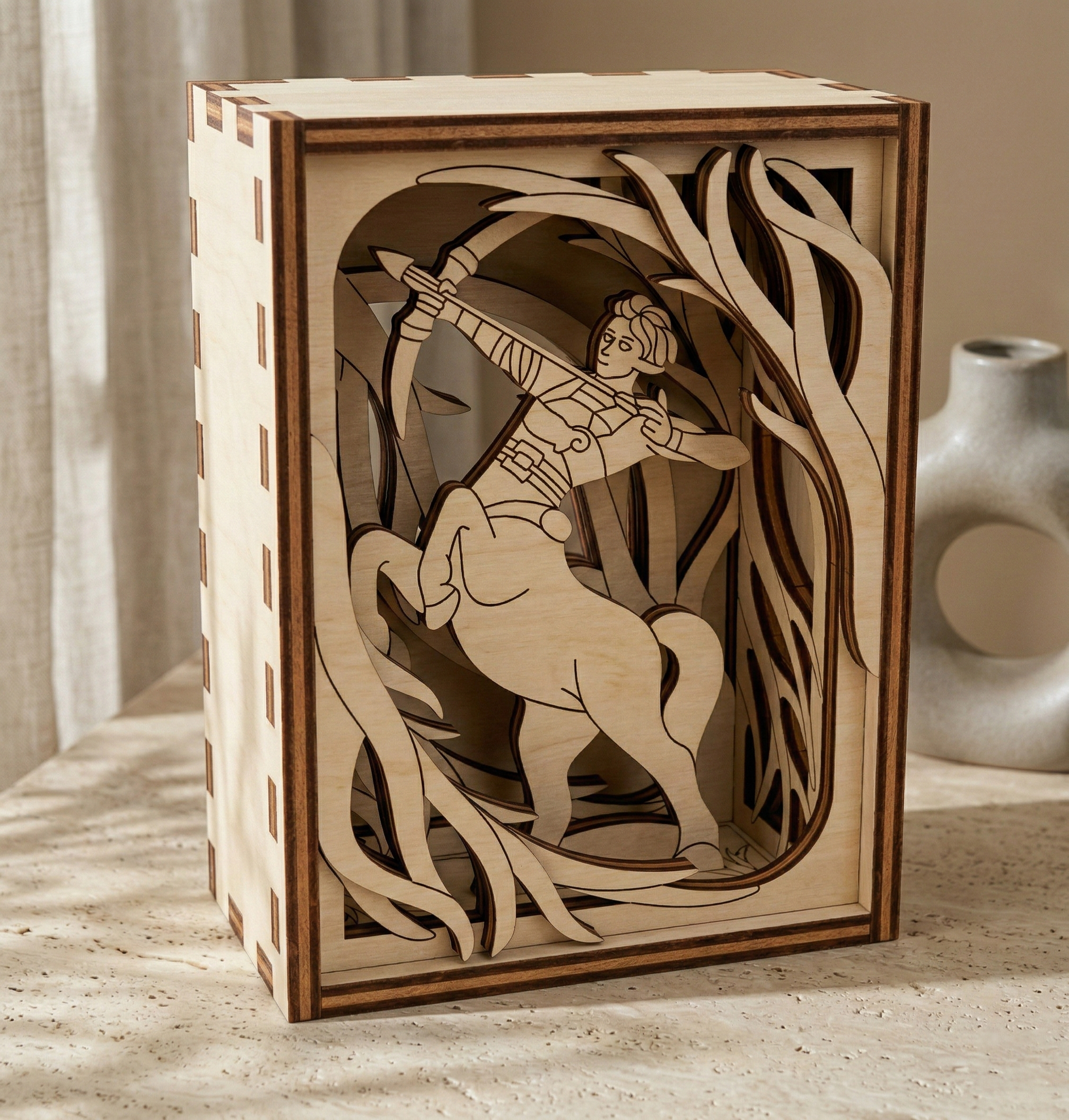 Wooden box with laser-cut design of a centaur archer and deer on a wooden surface.