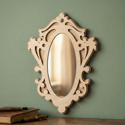 Elegant laser cut wooden Mirror ornaments with a curved frame design, set against a green wall background.