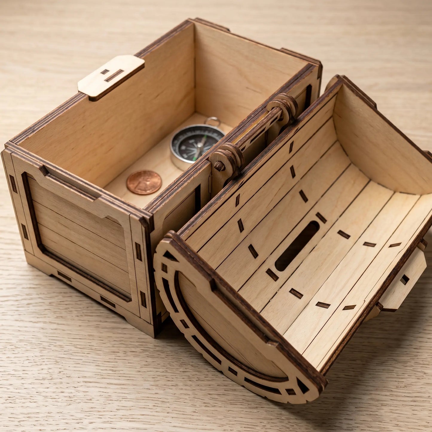 Wooden treasure chest model with a compass and coin on a wooden surface