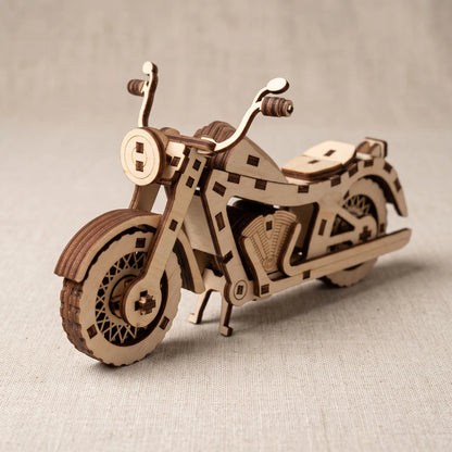 A wooden laser-cut 3D model of motorcycle, displayed on a neutral beige textured fabric background.