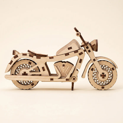 A wooden laser-cut model of motorcycle, constructed from light-colored plywood with darker brown laser-burned edges, displayed on a clean, solid cream background.