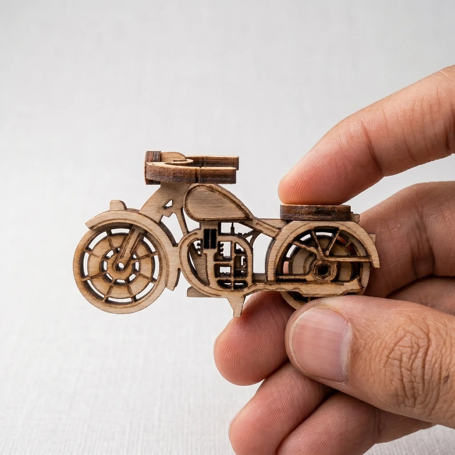 Wooden motorcycle model held by a hand against a white background