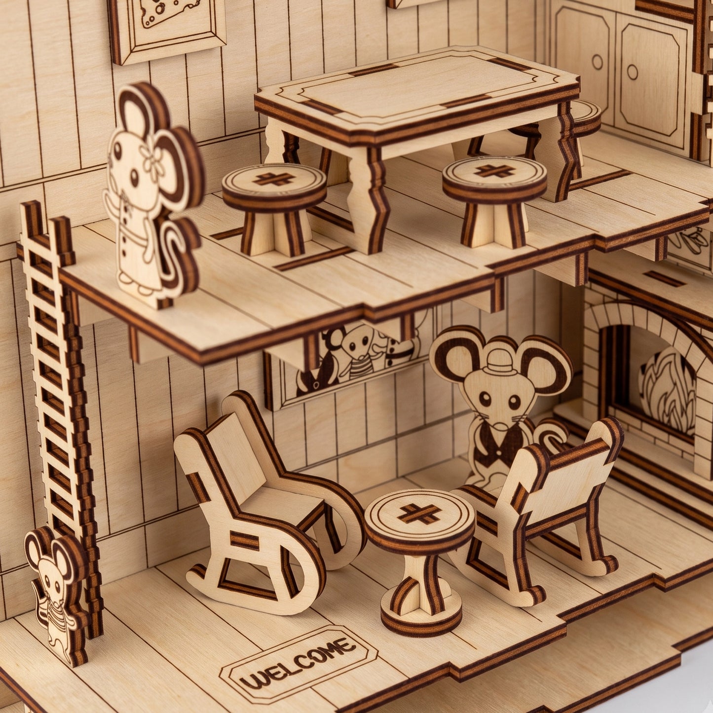 Close-up of a laser-cut birch plywood mouse house model featuring tiny furniture, miniature mouse figurines, and dark burnt edges.
