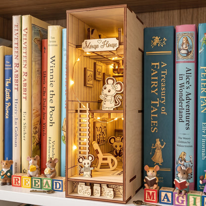 Lit laser-cut birch plywood mouse house book nook styled on a shelf with storybooks, letter blocks, and miniature toy mice