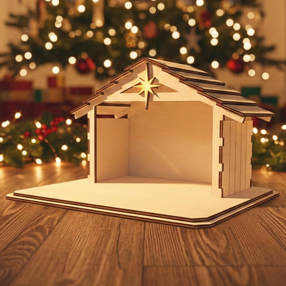 Wooden laser cut Nativity barn #2 with shingled roof, glowing Bethlehem star on the front, and open stable design, shown against a softly blurred Christmas tree background.