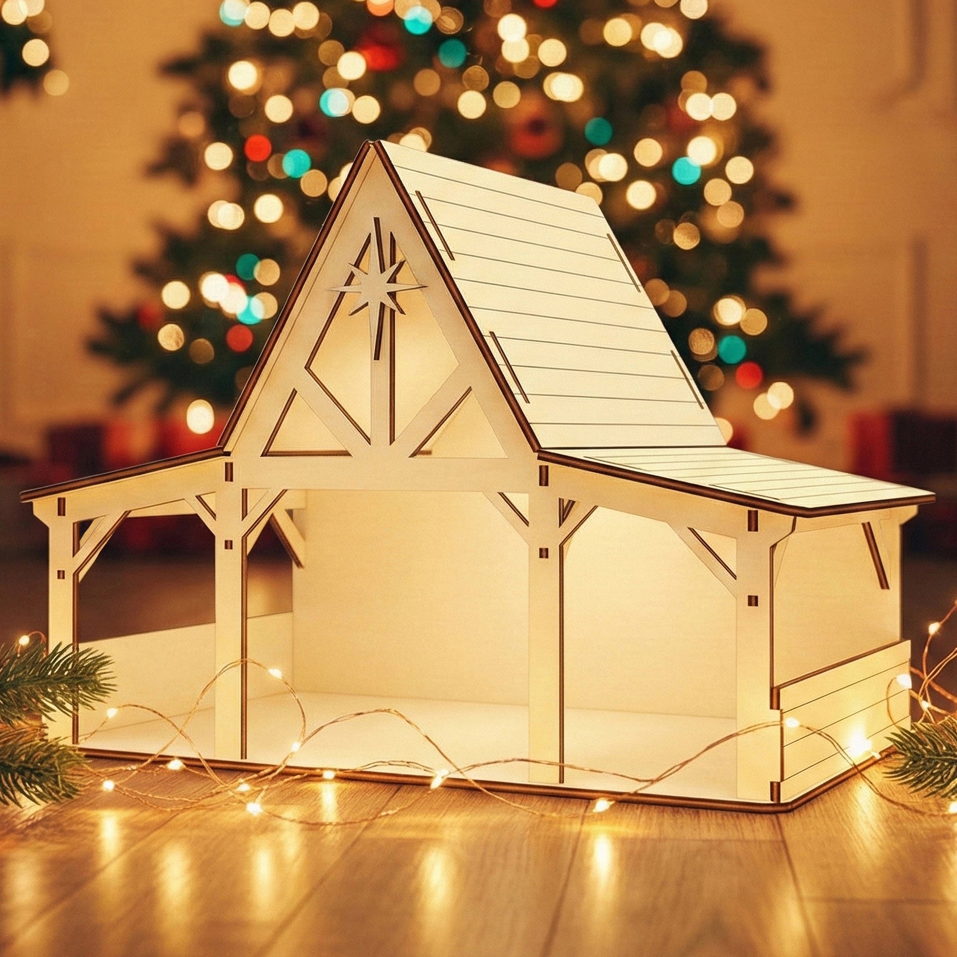 Wooden laser cut Nativity barn #4 with timber-framed open sides, extended roof overhang, and prominent star detail on the gable, warmly illuminated against a softly blurred Christmas tree background.