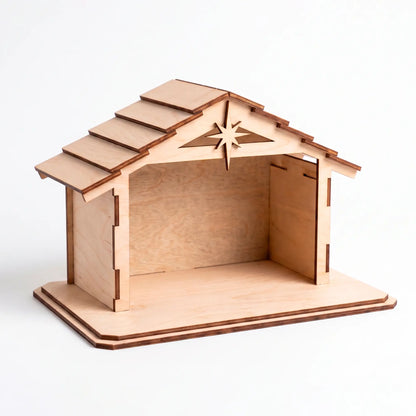 Front view of an empty laser cut plywood nativity stable showing detailed roof shingles and a star on a white background