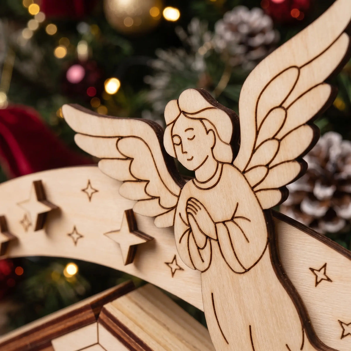 Macro of laser cut plywood praying angel on curved star arch, showing fine engraved details on wood.