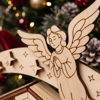 Macro of laser cut plywood praying angel on curved star arch, showing fine engraved details on wood.