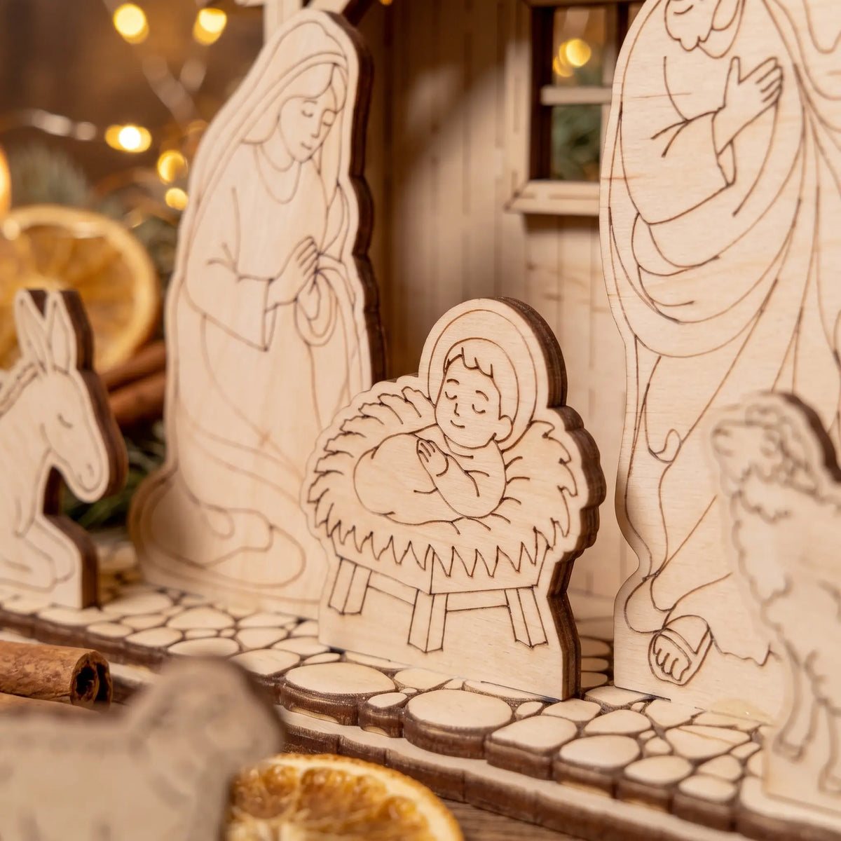Close-up of laser cut plywood baby Jesus in a manger surrounded by Mary, Joseph, and cobblestones.
