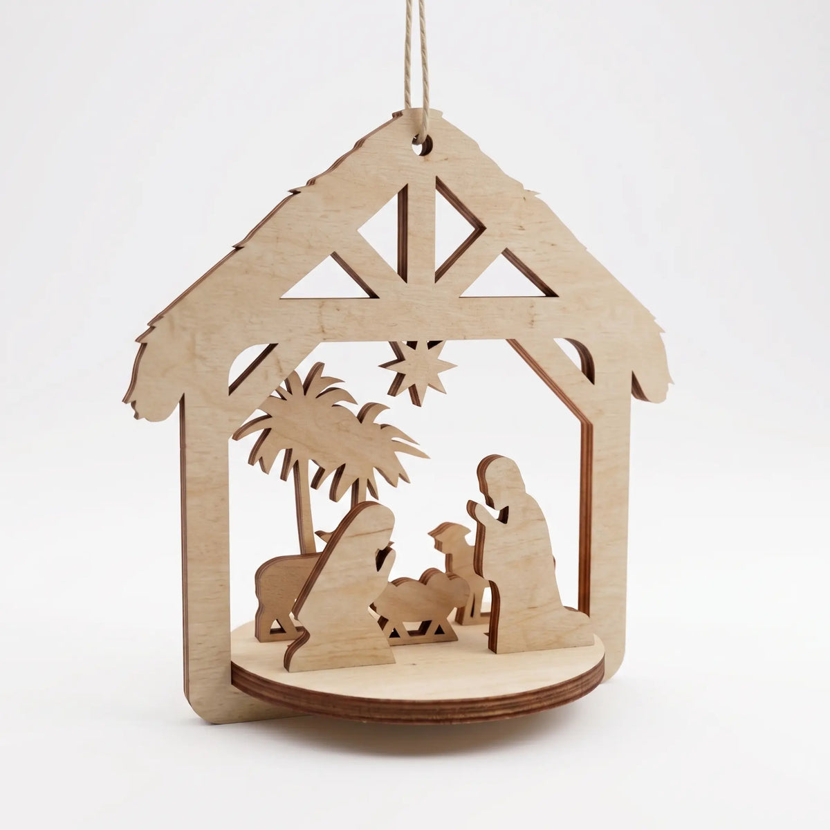 3D laser cut plywood nativity stable ornament with holy family silhouette figures on round base, on plain white