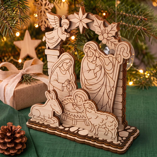 Side angle of laser cut plywood layered nativity set on holiday table with pine branch and gift box.