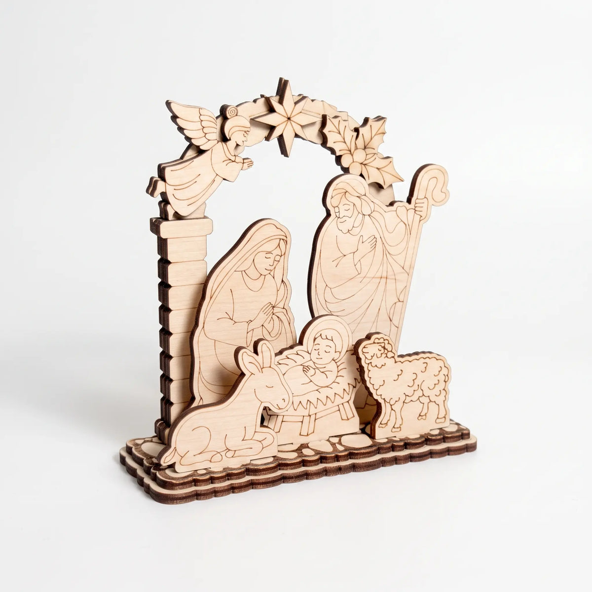 Perspective shot of multi-layer laser cut plywood Christmas nativity ornament on clear white backdrop.