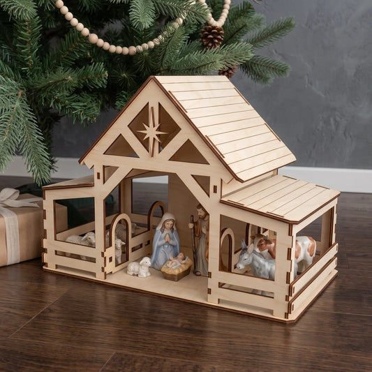 Assembled laser cut plywood stable with holy family figurines under pine tree on wooden floor by gifts.