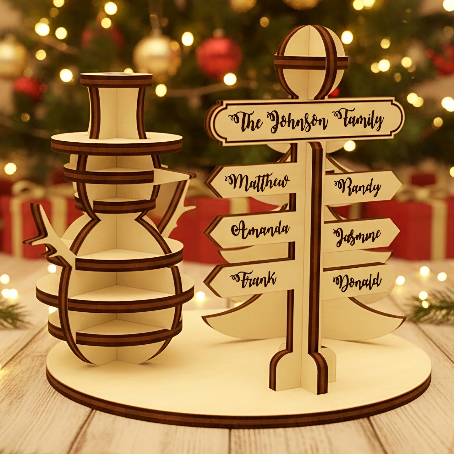 Wooden laser cut North Pole Family Sign featuring a smiling snowman and a personalized directional signpost with family names, displayed against a festive blurred Christmas tree background.