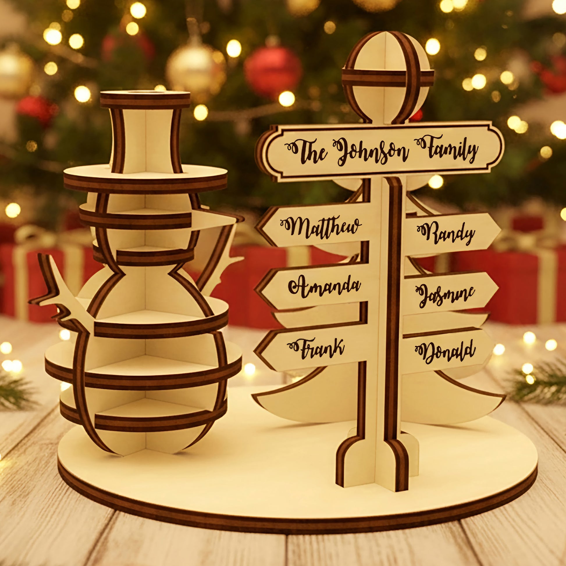 Wooden laser cut North Pole Family Sign featuring a smiling snowman and a personalized directional signpost with family names, displayed against a festive blurred Christmas tree background.