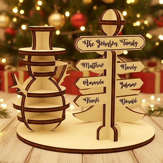 Wooden laser cut North Pole Family Sign featuring a smiling snowman and a personalized directional signpost with family names, displayed against a festive blurred Christmas tree background.