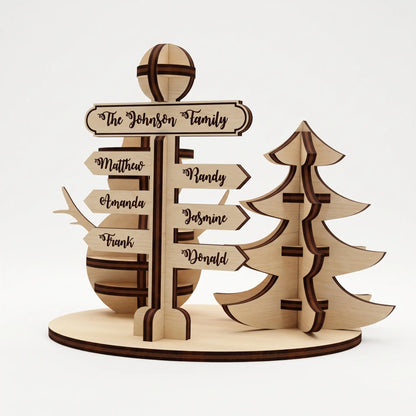 Front view of laser cut plywood family signpost kit with slotted tree and snowman on round stand on white.