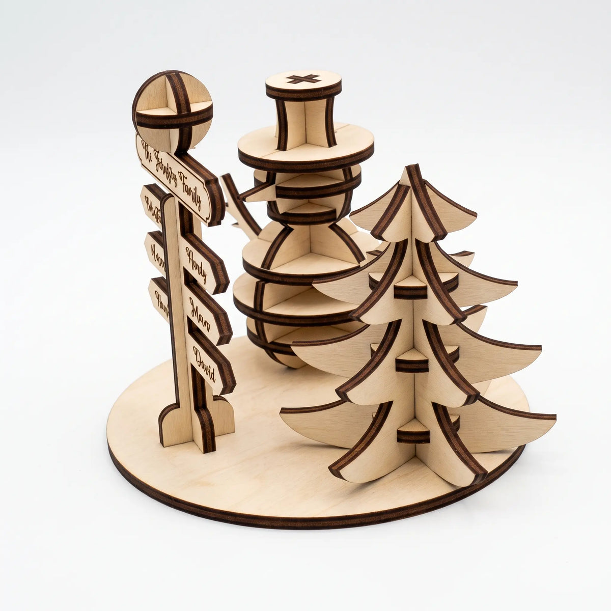 High-angle perspective view of assembled laser cut plywood snowman, signpost, and pine tree centerpiece on white.