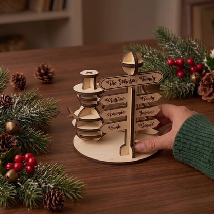 Hand places personalized laser cut plywood North Pole family signpost table centerpiece near holiday greenery