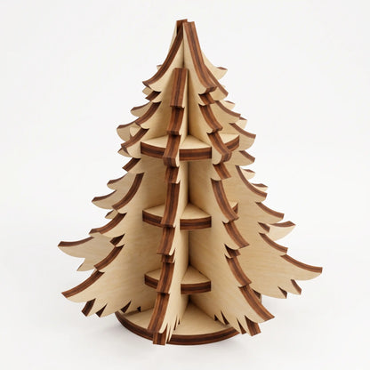3D layered laser cut plywood miniature Christmas tree ornament with burnt laser edges standing on white background.
