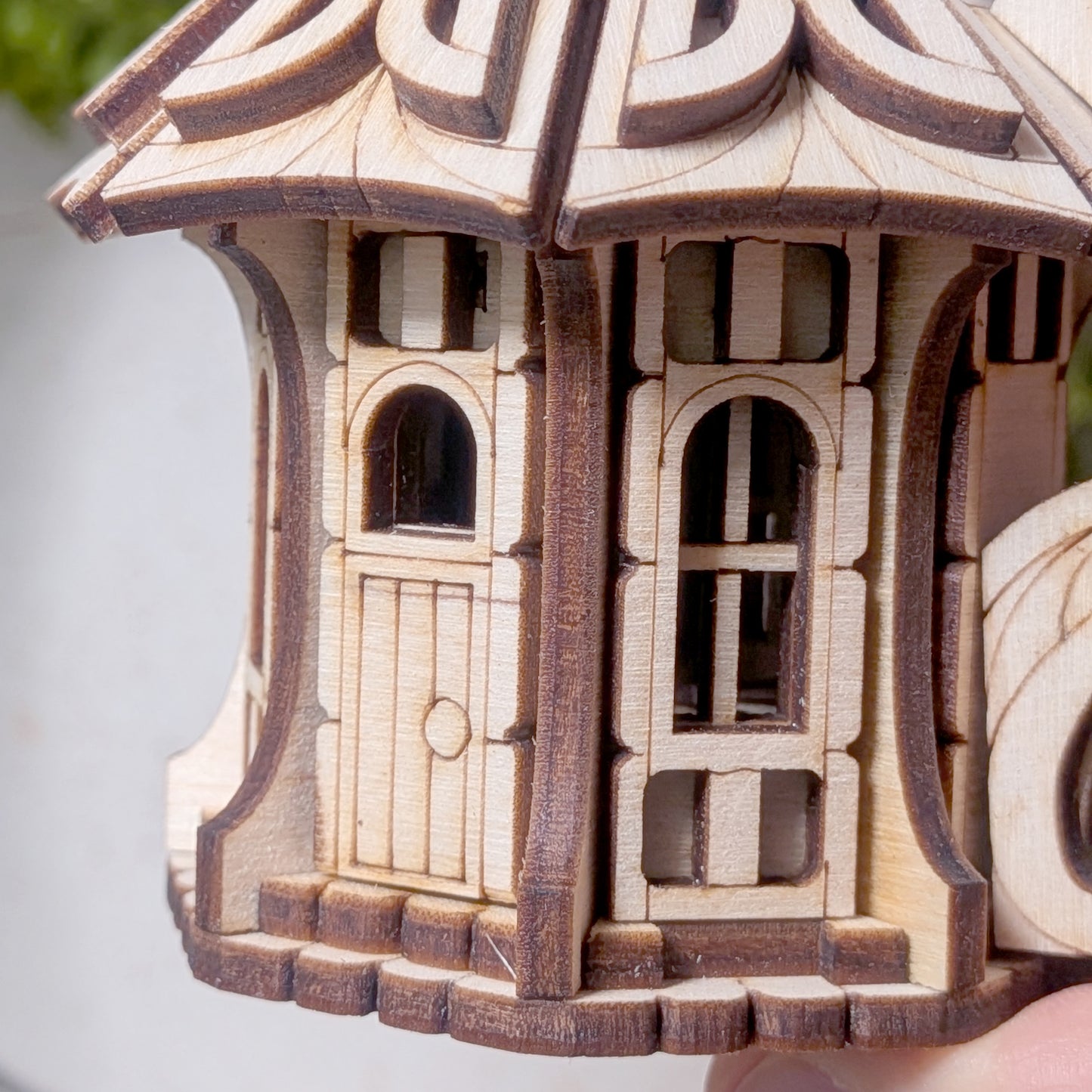 Macro close-up of the fairy house doorway and windows, showing precision laser-cut plywood details
