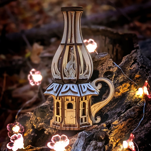 Wooden oil-lamp shaped fairy house made from laser-cut plywood, displayed outdoors on a tree stump with warm glowing lights