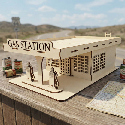 Miniature vintage gas station model made from laser cut plywood with a red "Gasoline" sign. A small blue vintage pickup truck is parked in front of the detailed service bay and office. The wood features realistic burnt edges and engraved textures.