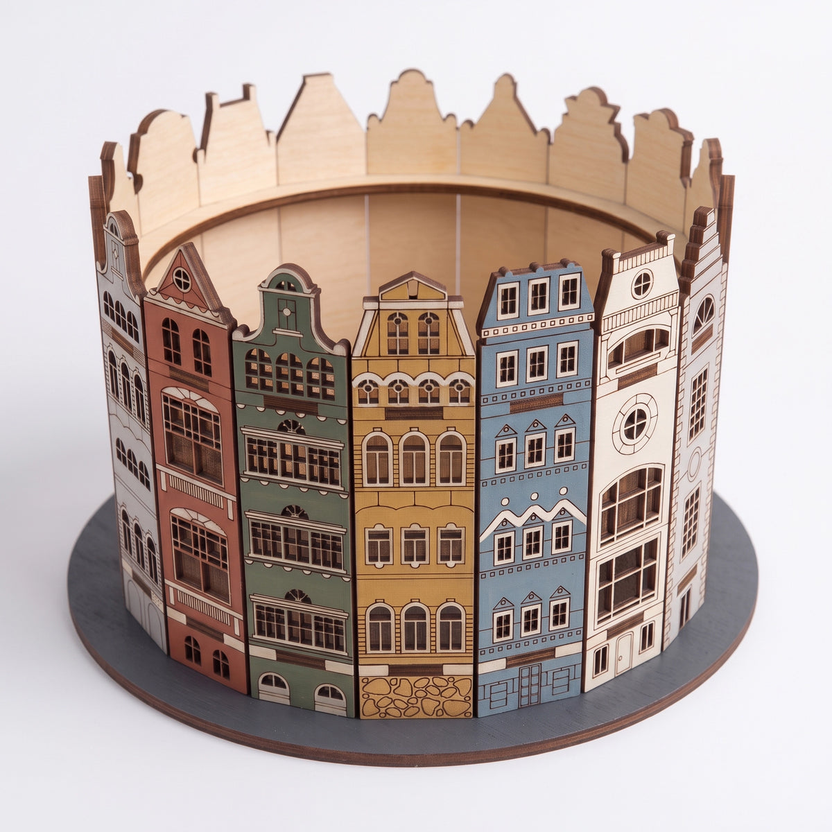 Round 3D laser cut plywood old town candy box featuring painted colorful European townhouse facades on a white backdrop.