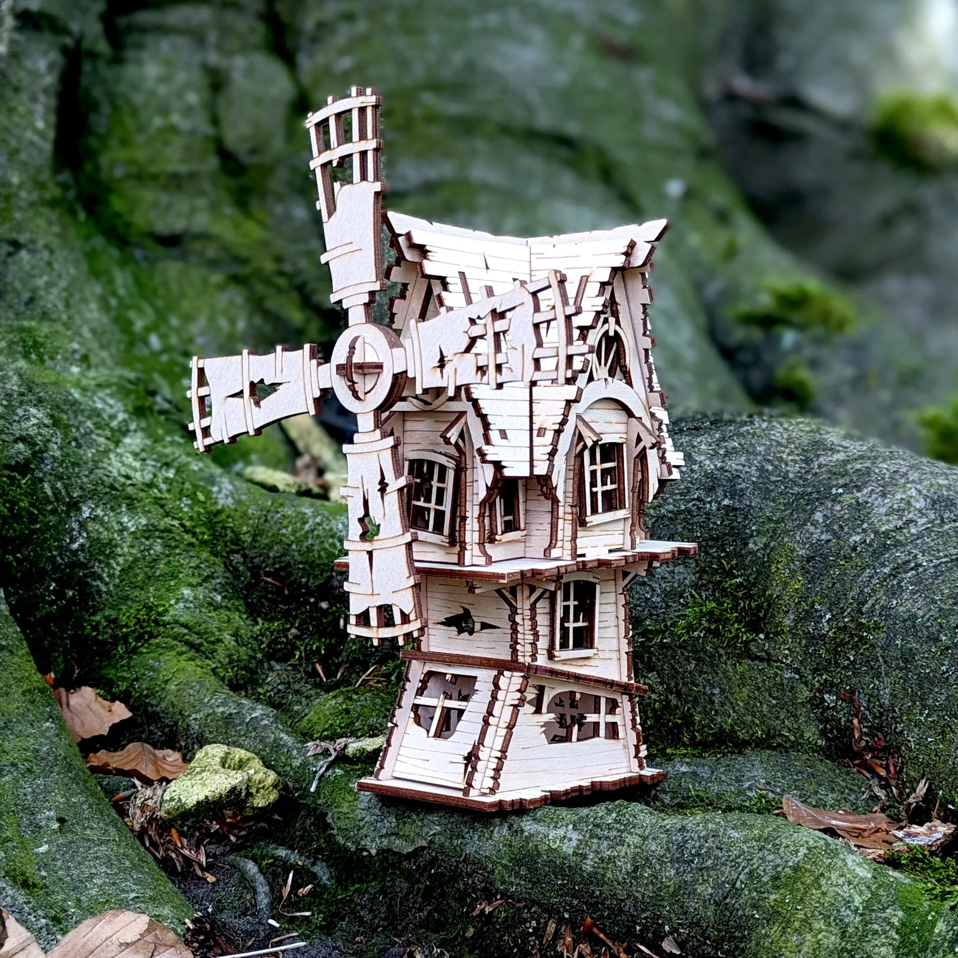 A stunning wide holiday staging product shot of an assembled miniature spooky windmill crafted from fine laser cut plywood.