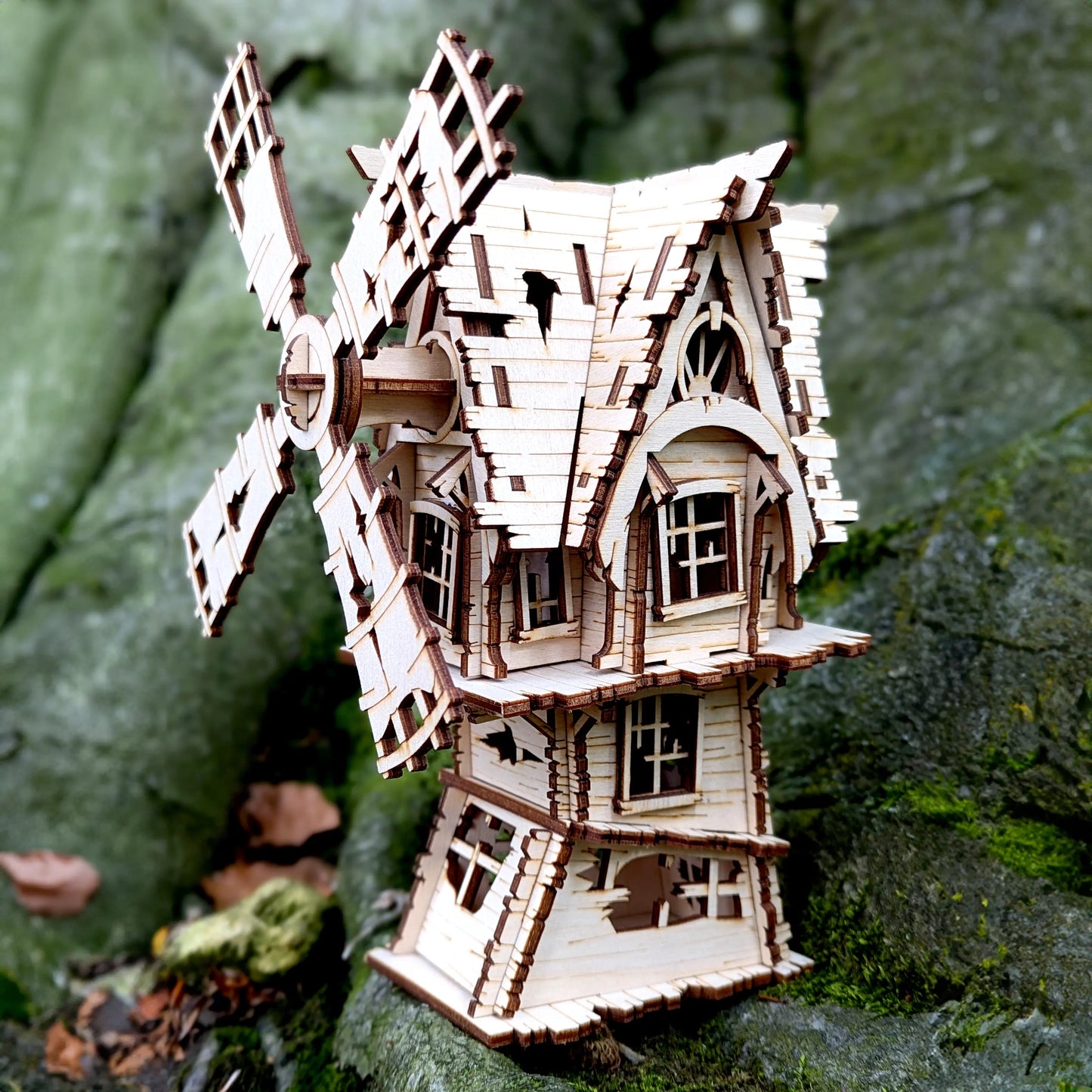 An atmospheric product photography photo of an assembled spooky 3D miniature holiday village laser cut plywood windmill.