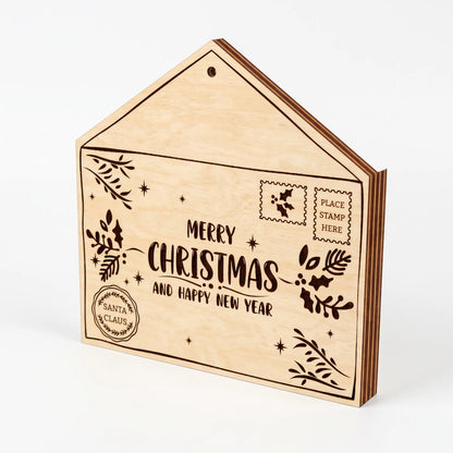 Side view of laser cut plywood Santa letter envelope box with Merry Christmas lettering on white surface.