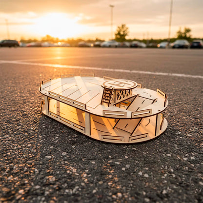 Laser cut wooden parking garage with a circular helipad and ladder. Top view shows parking lane markings and a ramp between levels. DIY plywood toy set for kids, photographed outdoors on pavement during golden hour