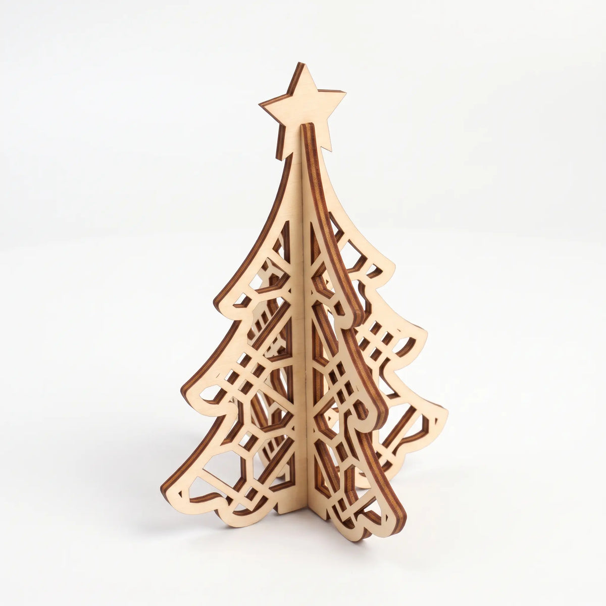 Isometric view of 3D laser cut plywood Christmas tree figurine with geometric lattice pattern on seamless white backdrop.