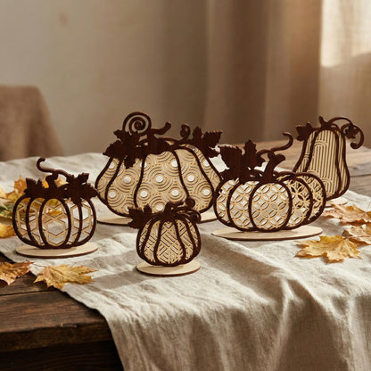 A collection of five laser cut plywood pumpkins in various sizes and geometric patterns, arranged on a linen tablecloth with autumn leaves. The wooden decor features dark brown frames and light wood inserts, showing a mix of sizes.