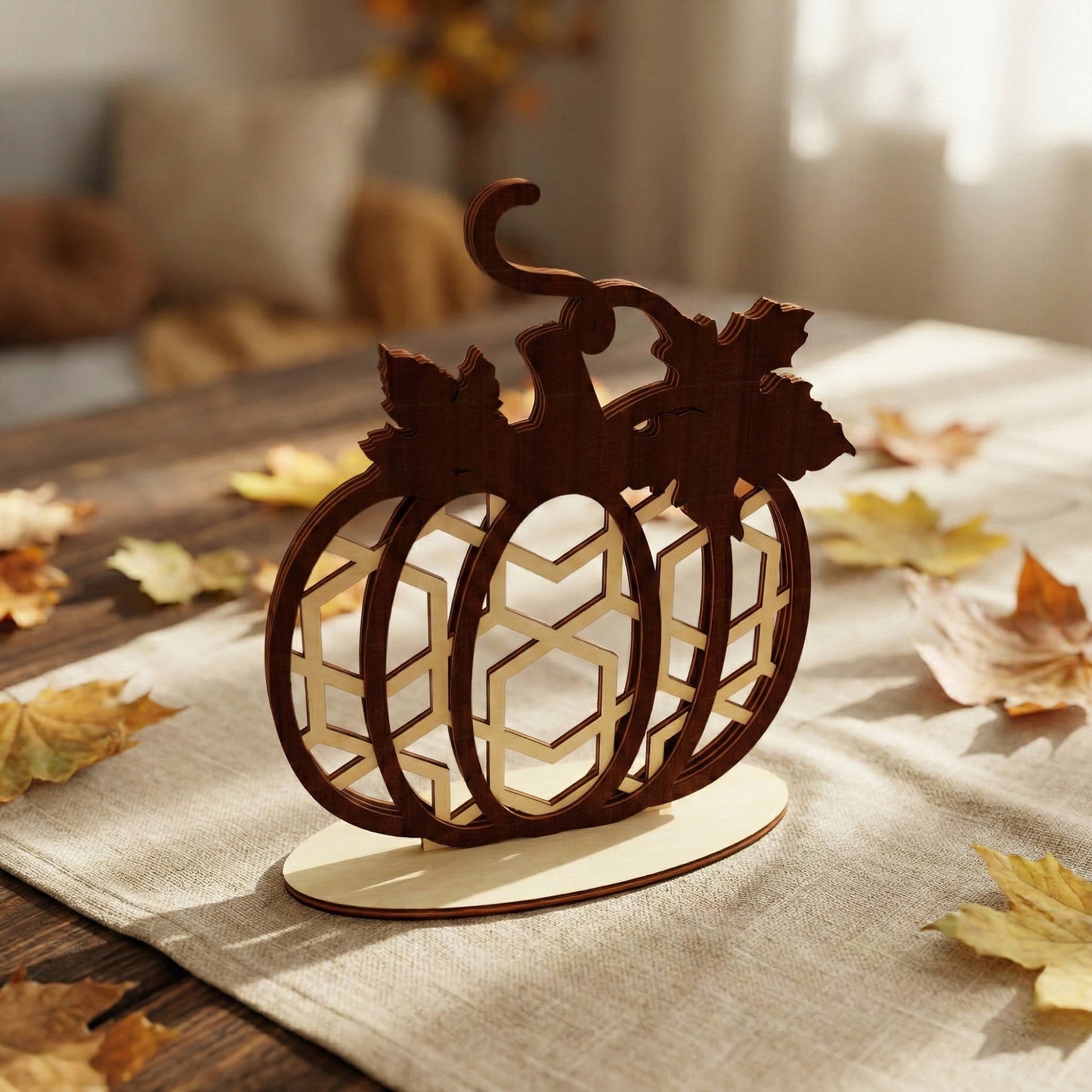 Wooden pumpkin decor made of laser cut plywood featuring a geometric honeycomb or hexagon pattern inside. The piece is mounted on an oval wooden base for stability. Soft indoor lighting emphasizes the warm textures of the birch wood.