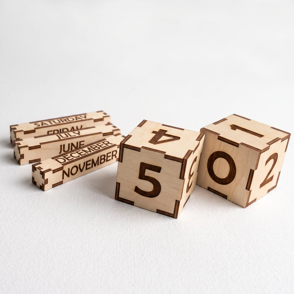 Engraved laser cut plywood perpetual calendar number blocks and month weekday slats arranged on plain white background.