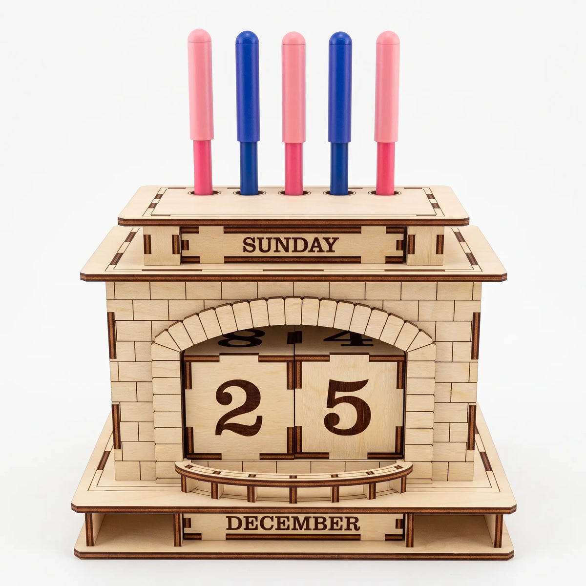 Front view of laser cut plywood fireplace perpetual calendar and pen holder stand holding five pens on white background.