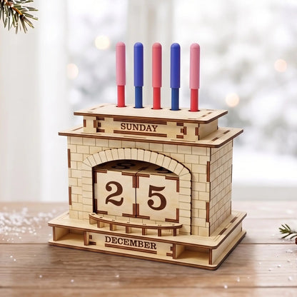 3D laser cut plywood fireplace perpetual calendar pen holder stand on wooden tabletop next to pine branch and snow.