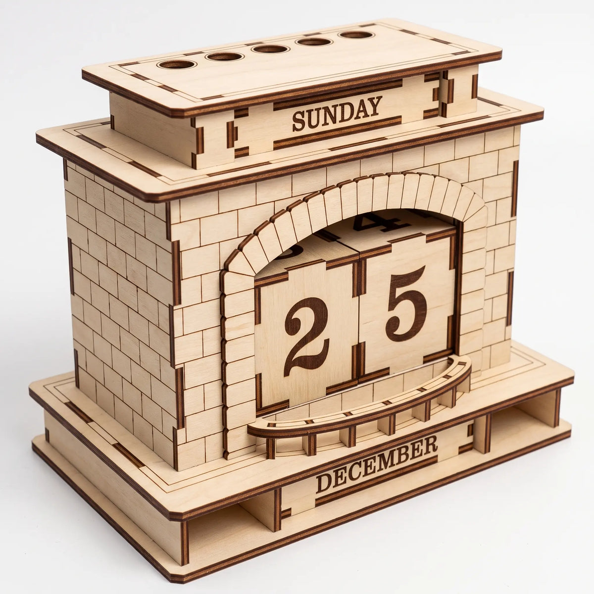 Perspective view of empty laser cut plywood fireplace perpetual calendar pen holder organizer on solid white backdrop.