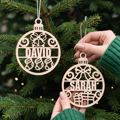 Hands display personalized laser cut plywood name baubles David and Sarah on an illuminated pine Christmas tree