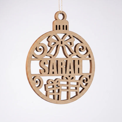 Angled view of laser cut plywood Sarah bauble with presents and bow cutout, suspended against a white backdrop.