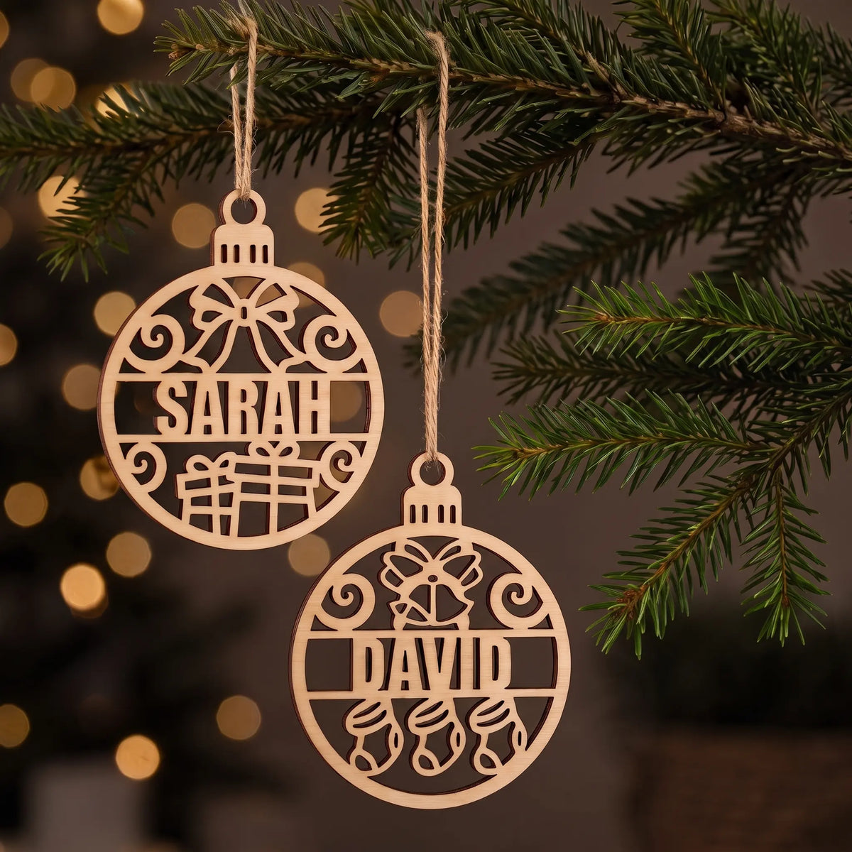 Personalized laser cut plywood baubles Sarah and David hanging together from evergreen branch before holiday lights.