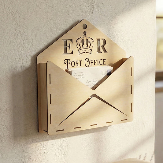 Wall-mounted laser cut plywood mail organizer shaped like an open envelope. Features "E R Post Office" and a crown cutout. Shown holding letters above a wooden bench with craft envelopes and lavender.