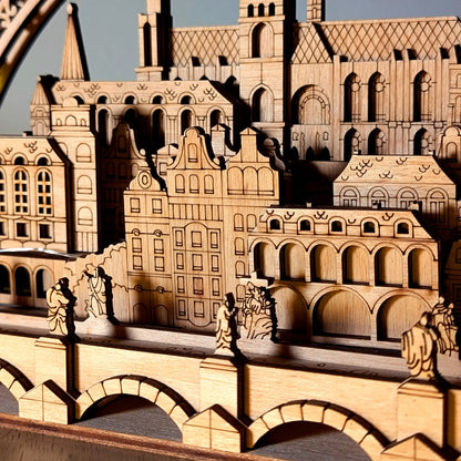 A detailed macro shot of miniature historical bridge statues in front of Prague old town facades made from laser cut plywood.